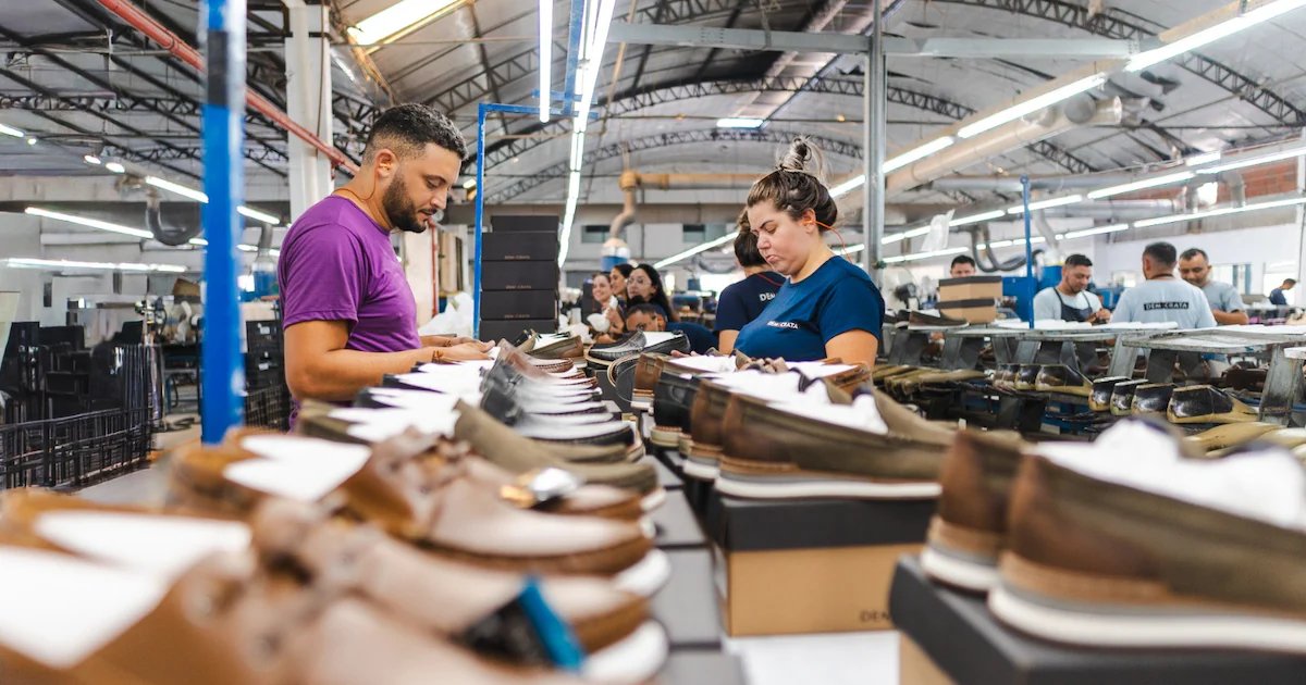 Trabalhadores conferem calçados em linha de produção de uma fábrica brasileira